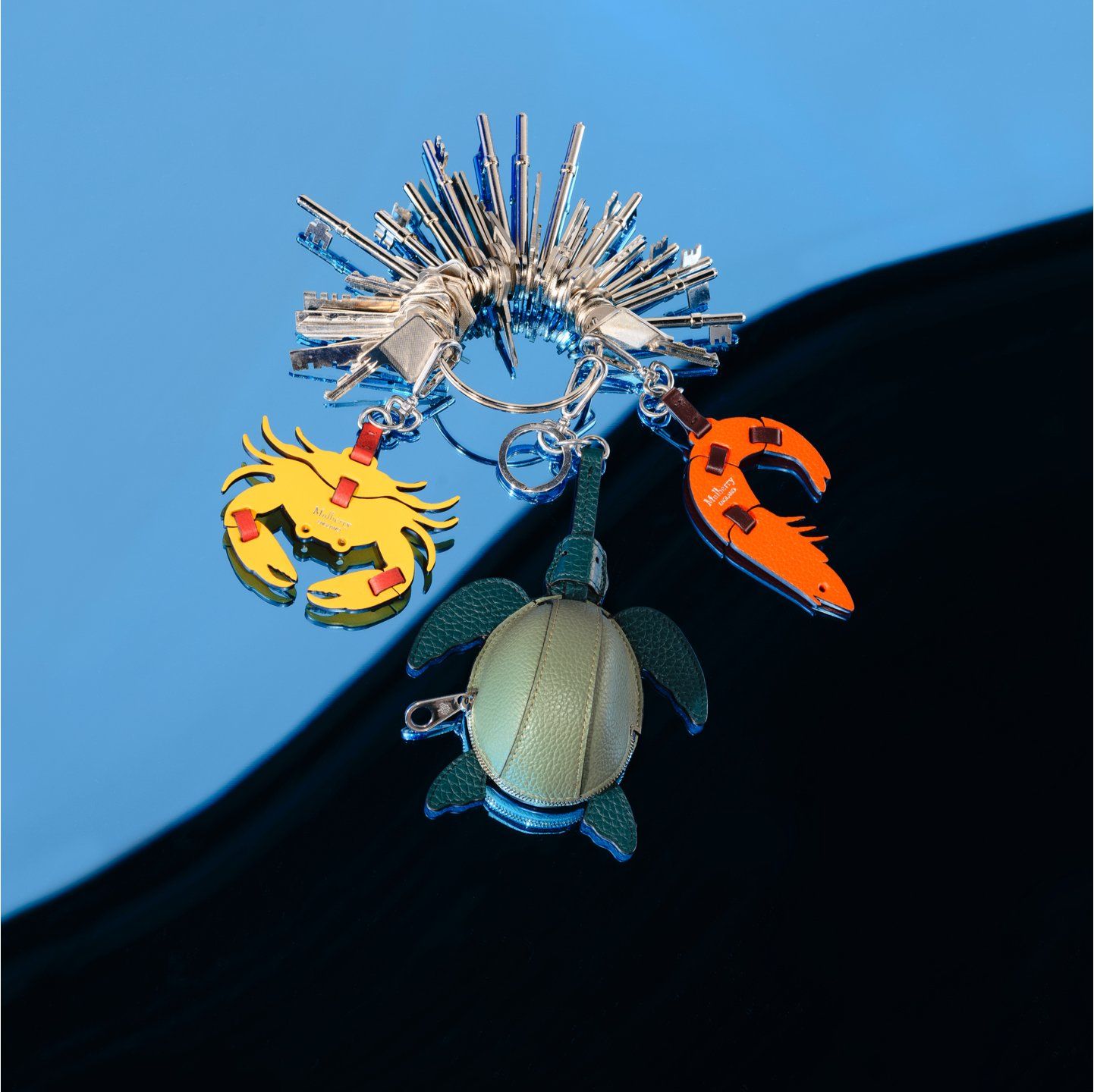 set of keys holding three mulberry keyrings, flat yellow crab keyring, green turtle case keyring and orange shrimp keyring